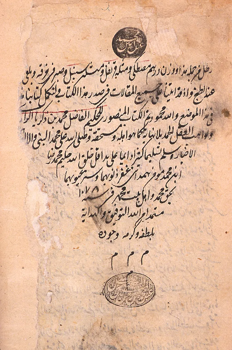 An aged manuscript page in Arabic script, the colophon of a copy of al-Razi's Book of Medicine for Mansur, bearing two circular seal stamps