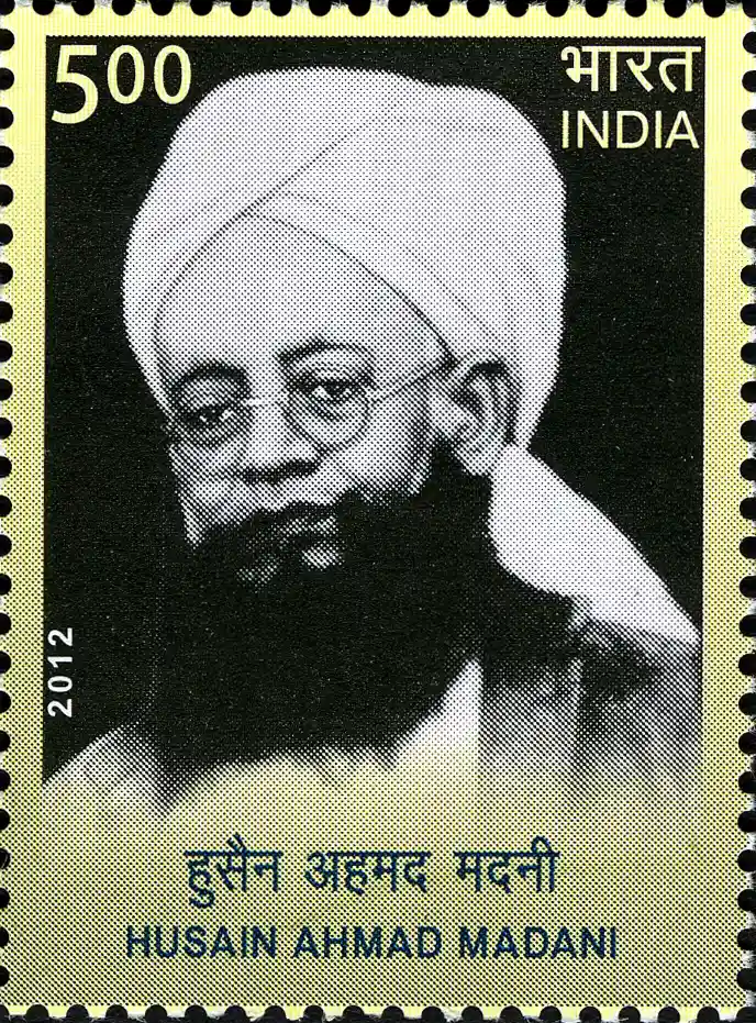An Indian commemorative postage stamp with a perforated edge, carrying a halftone black and white portrait of a bearded man in a white turban wearing round spectacles, with the figure 5.00 at the upper left, the year 2012 down the left edge and his name in Devanagari and Roman letters beneath